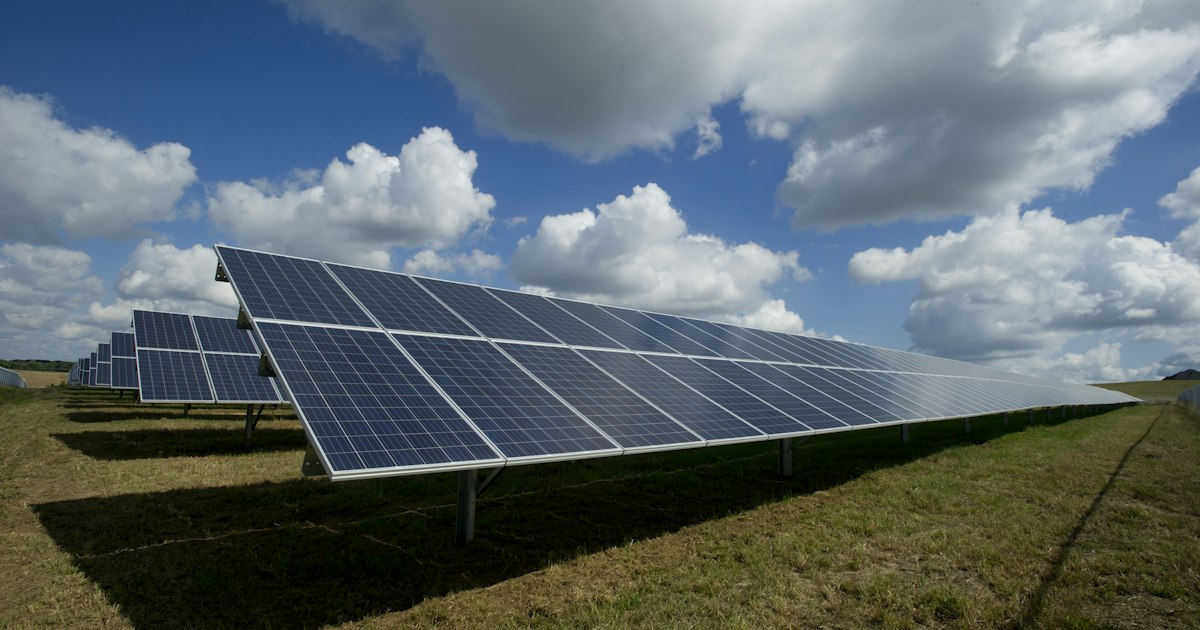 Amplio arreglo de paneles solares reflejando luz en una planta fotovoltaica a escala industrial